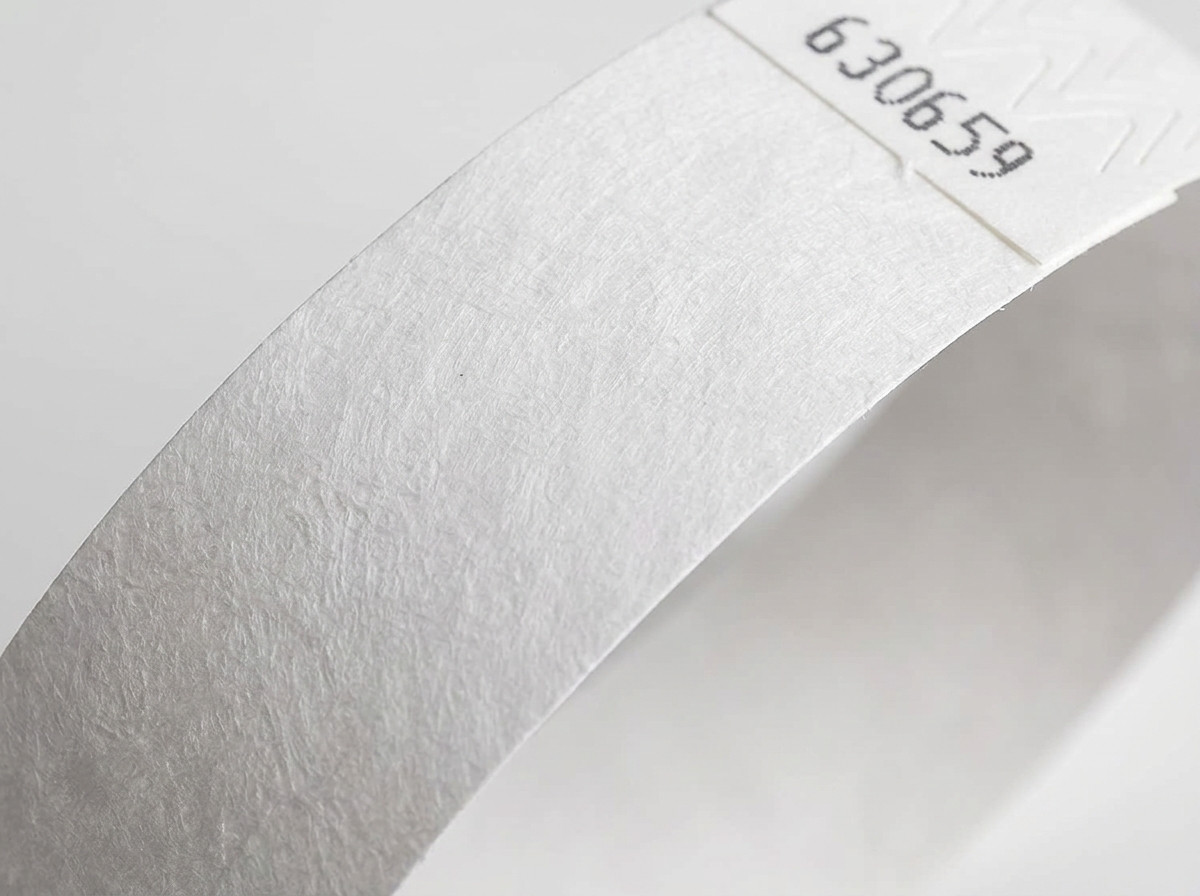 Detail povrchu netkané textílie bieleho náramku Tyvek zobrazujúci charakteristickú textúru polyetylénu s vysokou hustotou